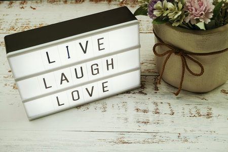 Live Laugh Love word in light box flat lay on wooden background