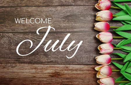 Welcome July text and tulip flower decoration on wooden backgroundの写真素材