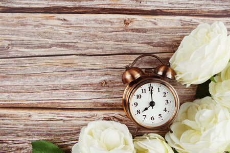 Alarm clock with White peony flowers border frame on wooden background