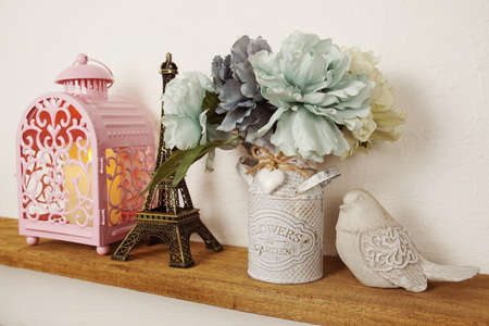 Wooden shelves decorated with Eiffel tower souvenir, candle light, flower bouquet and bird statueの写真素材