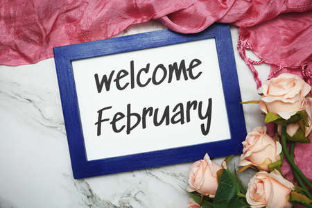 Welcome February written on blue frame with rose flower flat lay on marble backgroundの写真素材