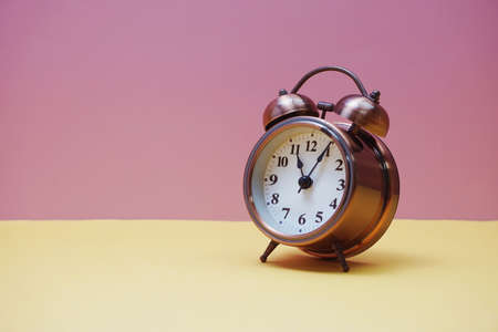 Vintage alarm clock with space copy on yellow and pink backgroundの写真素材
