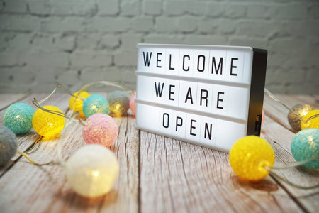 Welcome We are Open text on lightbox on wooden background