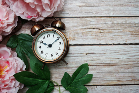 Alarm clock with pink peony flowers border frame on wooden backgroundの写真素材