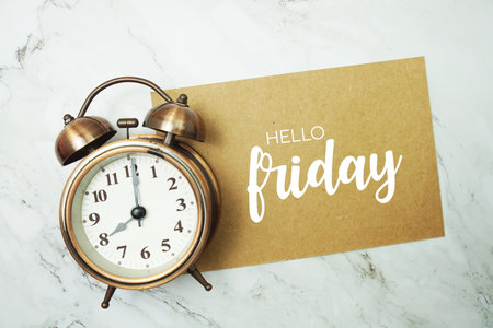 Hello Friday typography text on paper card with alarm clock on marble backgroundの写真素材