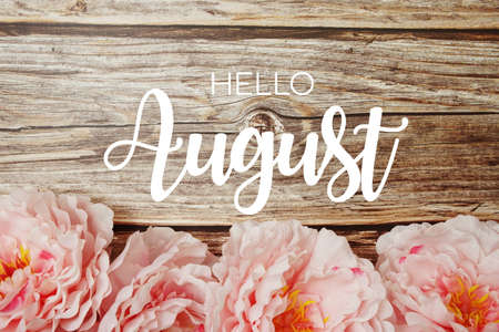 Welcome August typography text with peony flowers on wooden backgroundの写真素材