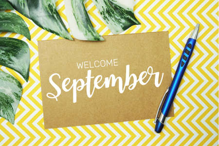 Welcome September typography text on paper card with alarm clock and Monstera leaveの写真素材