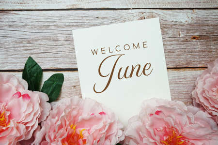 Welcome June card typography text with flower bouquet on wooden backgroundの写真素材