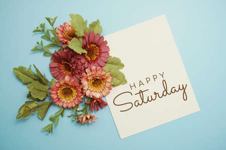 Happy Saturday card typography text with flower bouquet on blue backgroundの写真素材
