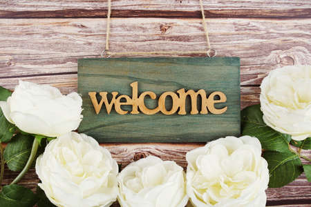 Welcome Sign and alarm clock with Flower Blooming Decoration on wooden backgroundの写真素材