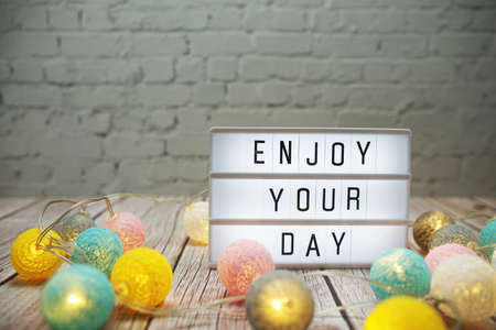 Enjoy Your Day text on lightbox on wooden backgroundの写真素材