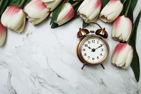 Vintage alarm clock and tulip flower bouquet on marble backgroundの写真素材