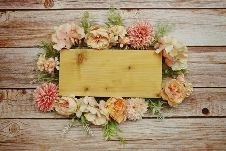 Frame of flowers with wooden banner for text on wooden backgroundの写真素材