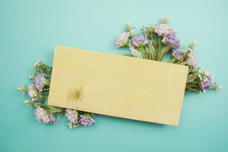 Frame of flowers with wooden banner for text on blue background