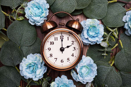 Alarm clock with eucalyptus leaves and flower decorate on wooden backgroundの写真素材