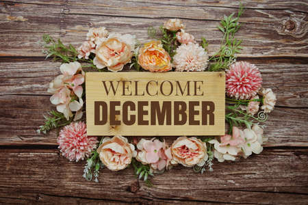 Welcome December text on wooden board with flowers frame on wooden backgroundの写真素材