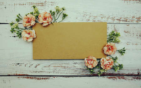 Frame of flowers with paper card for text on wooden backgroundの写真素材