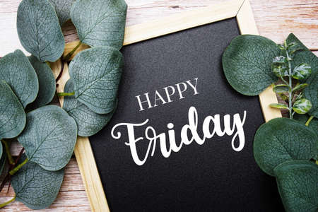 Happy Friday typography text and eucalyptus leaves border frame on wooden backgroundの写真素材