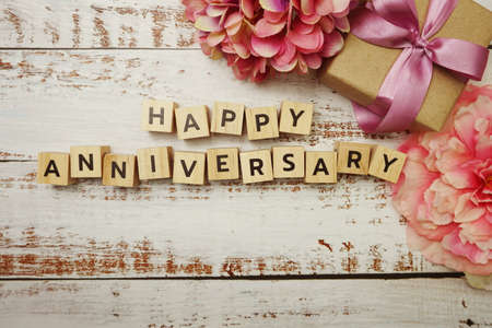 Happy Anniversary alphabet letter with gift box on wooden backgroundの写真素材
