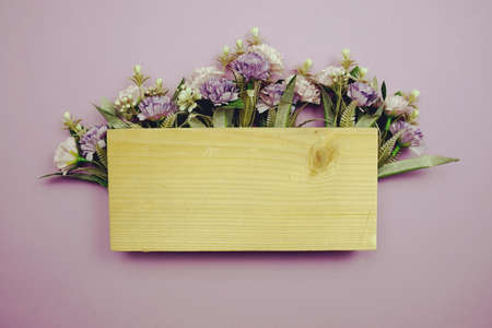 Frame of flowers with wooden banner for text on purple backgroundの写真素材