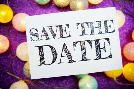 Save The Date text on paper card top view on purple bokeh backgroundの写真素材