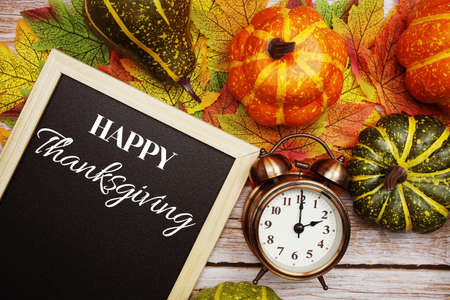 Happy Thanksgiving text on blackboard decorate with maple leaves and pumpkin on wooden backgroundの写真素材