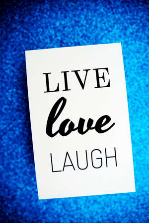 Live Love Laugh text on paper card top view on blue bokeh backgroundの写真素材