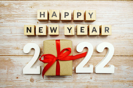 Happy New Year 2022 alphabet letters and gift box presents on wooden background