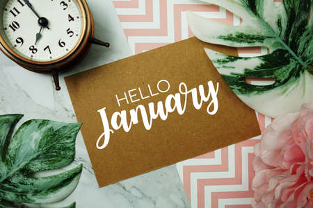 Hello January typography text on paper card with alarm clock and Monstera leaveの写真素材
