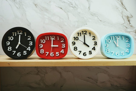 Clocks with time zone of different country on wooden shelves and marble background