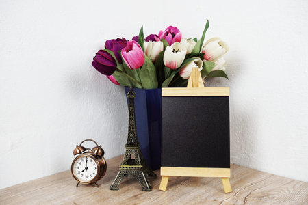 Empty easel chalkboard sign mockup with alarm clock, eiffel and flower decoration