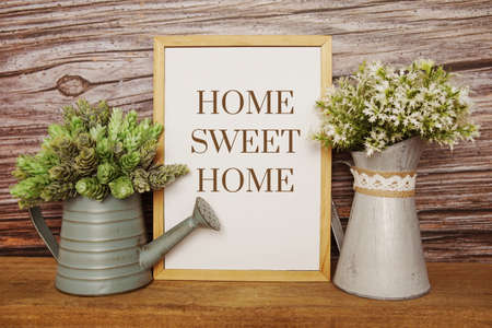 Blackboard with the text HOME SWEET HOME decorate with artificial plant in watering plant on wooden backgroundの写真素材