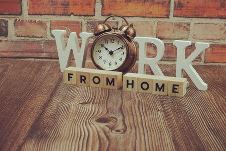 Work from Home alphabet letters with alarm clock on wooden background