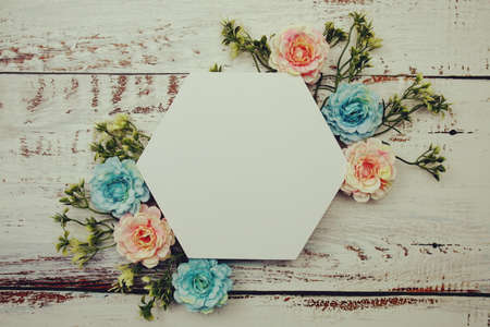Frame of flowers with paper card for text on wooden backgroundの写真素材