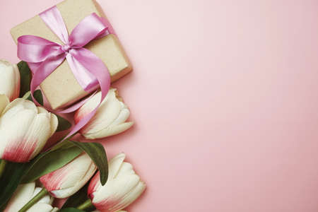 Gift boxes with pink ribbon and tulip flower bouquet on pink backgroundの写真素材