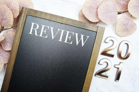 Review 2021 with space copy on blackboard with eucalyptus leaves on marble backgroundの写真素材