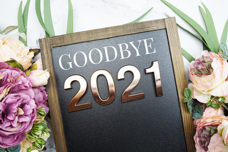 Goodbye 2021 text on blackboard with flower decoration on marble backgroundの写真素材