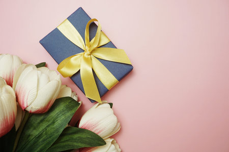 Blue Gift boxes with gold ribbon and tulip flower bouquet on pink background