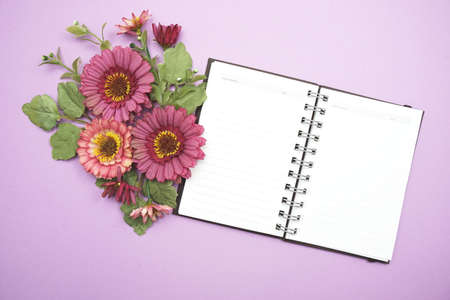 Empty Notebook with flower bouquet on purple backgroundの写真素材