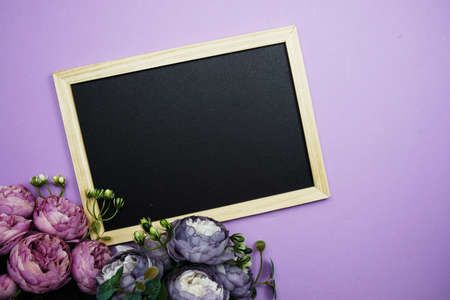 Empty Blackboard with flower bouquet on purple backgroundの写真素材