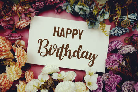 Happy Birthday typography text with flowers frame on pink backgroundの写真素材
