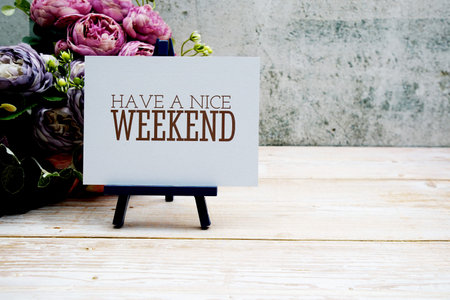 Have a Nice Weekend text on paper card with flower bouquet decoration on wooden background