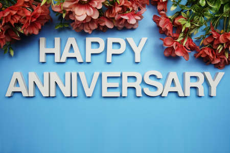 Happy Anniversary alphabet letters decorate with flowers on blue backgroundの写真素材