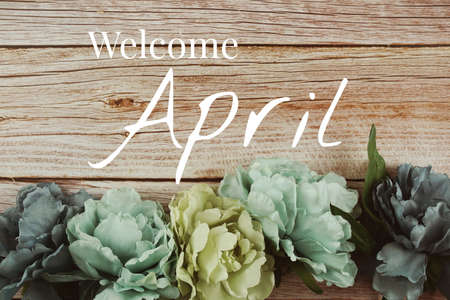 Welcome April typography text with blue flowers bouquet on wooden backgroundの写真素材