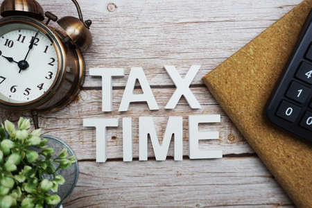 Tax Time alphabet letters with calculator and alarm clock on wooden backgroundの写真素材