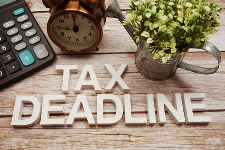 Tax Deadline alphabet letters with calculator and alarm clock on wooden backgroundの写真素材