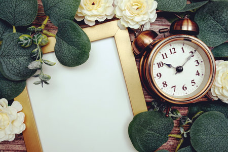 Empty space for copy with alarm clock, flower and eucalyptus leaves decoration on wooden backgroundの写真素材