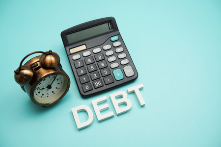 Debt alphabet letters with alarm clock and calculator on blue backgroundの写真素材