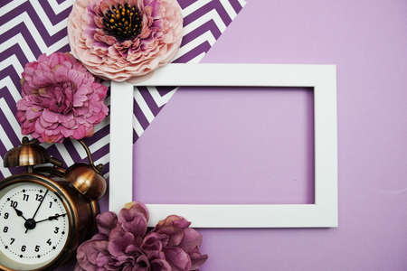 White Frame with alarm clock and flower decoration on purple backgroundの写真素材