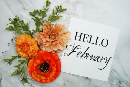 Hello February text with orange flower bouquet on marble backgroundの写真素材